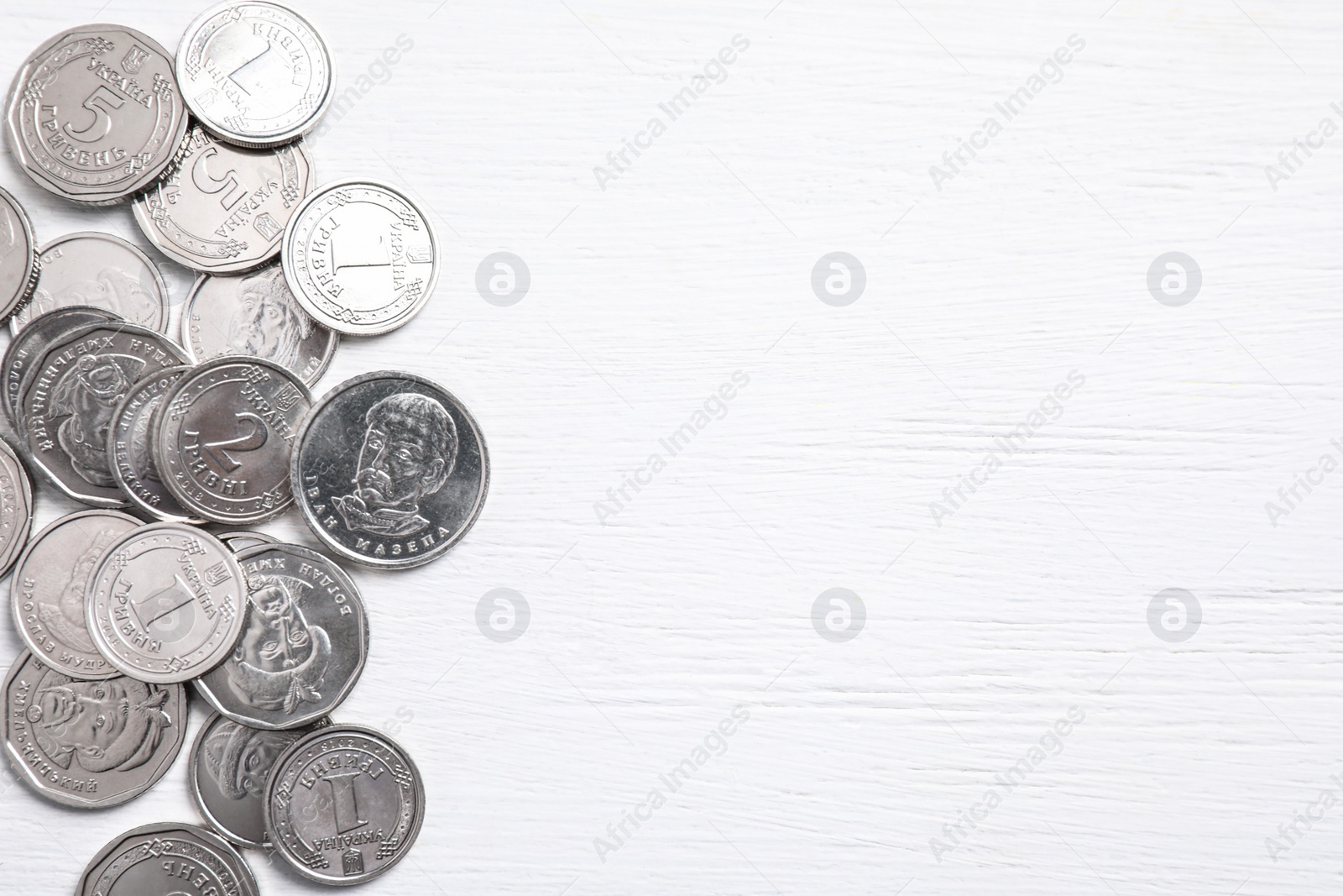 Ukrainian coins on white wooden background, flat lay. Space for text Photo of Ukrainian coins on white wooden background, flat lay. Space for text