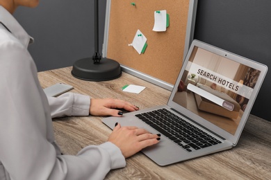 Woman searching hotel using laptop at table, closeup. Booking online service Image of Woman searching hotel using laptop at table, closeup. Booking online service