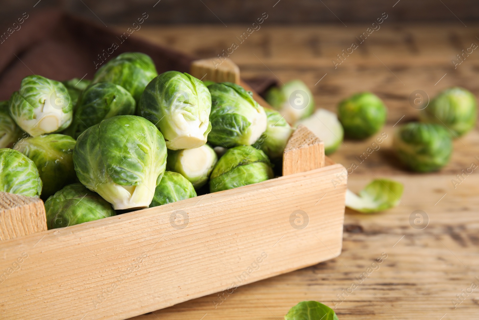 Crate with fresh Brussels sprouts on wooden table, closeup Photo of Crate with fresh Brussels sprouts on wooden table, closeup