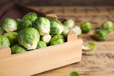 Crate with fresh Brussels sprouts on wooden table, closeup Photo of Crate with fresh Brussels sprouts on wooden table, closeup