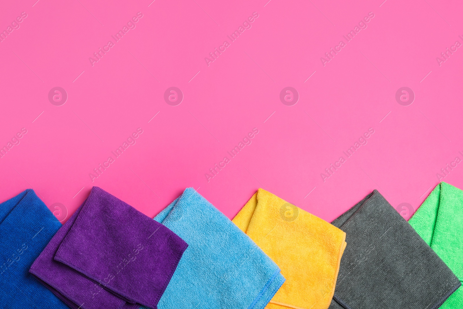 Many colorful microfiber cloths on pink background, flat lay. Space for text Photo of Many colorful microfiber cloths on pink background, flat lay. Space for text