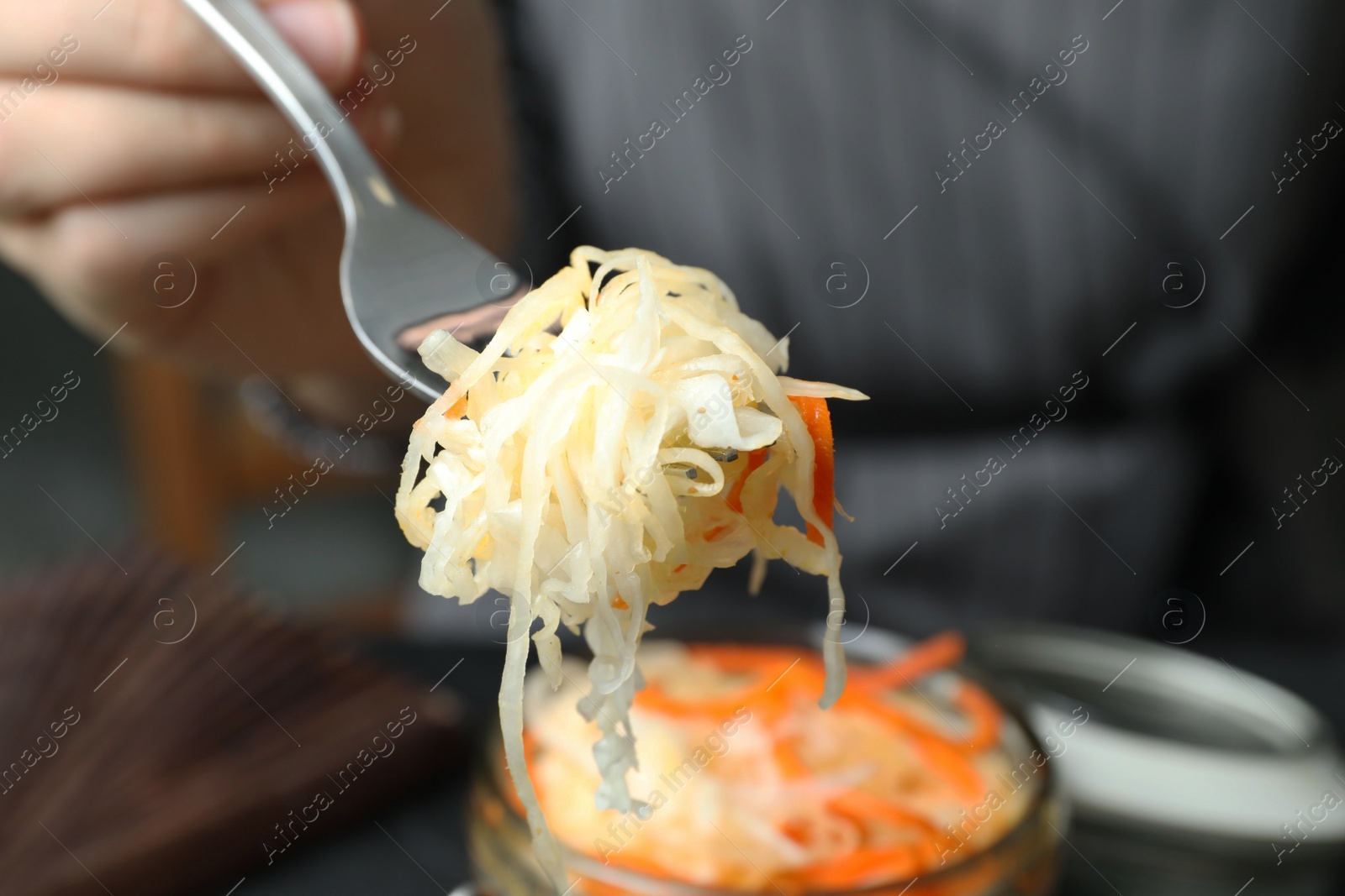 Woman holding fork with fermented cabbage, closeup Photo of Woman holding fork with fermented cabbage, closeup