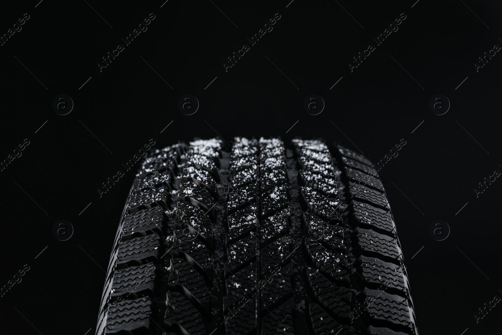 Snowy winter tire on black background, closeup Photo of Snowy winter tire on black background, closeup
