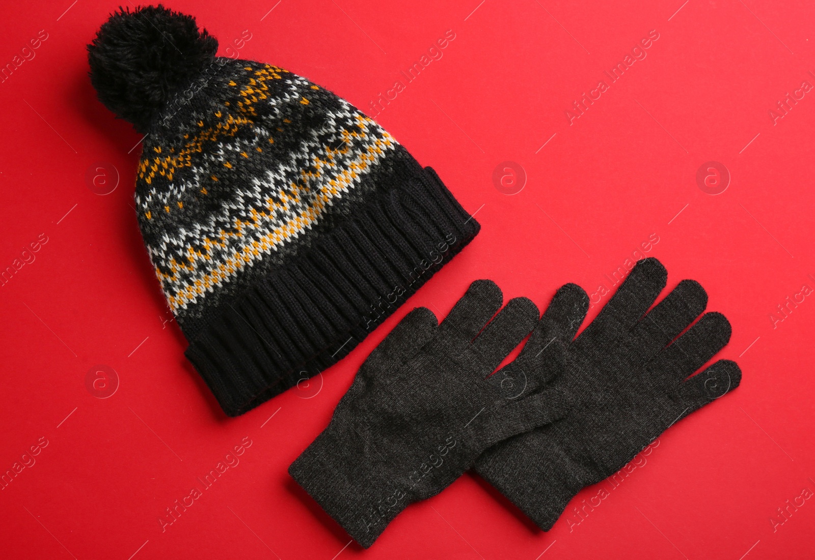 Woolen gloves and hat on red background, flat lay Photo of Woolen gloves and hat on red background, flat lay