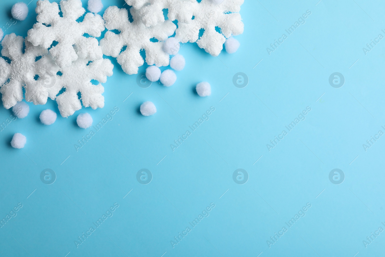 Beautiful snowflakes and decorative balls on light blue background, flat lay. Space for text Photo of Beautiful snowflakes and decorative balls on light blue background, flat lay. Space for text
