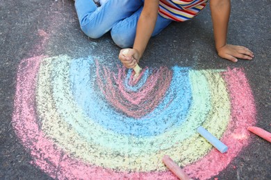 Little child drawing rainbow with colorful chalk on asphalt, closeup Photo of Little child drawing rainbow with colorful chalk on asphalt, closeup