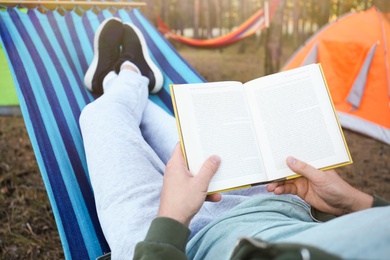 Man with book resting in comfortable hammock outdoors, closeup Photo of Man with book resting in comfortable hammock outdoors, closeup