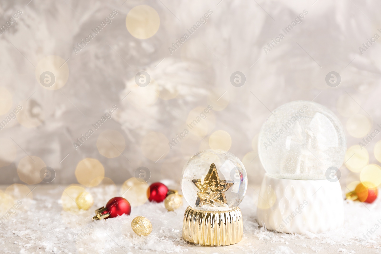 Beautiful Christmas snow globes and ornaments on light table, bokeh effect. Space for text Image of Beautiful Christmas snow globes and ornaments on light table, bokeh effect. Space for text