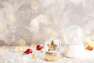 Beautiful Christmas snow globes and ornaments on light table, bokeh effect. Space for text Image of Beautiful Christmas snow globes and ornaments on light table, bokeh effect. Space for text