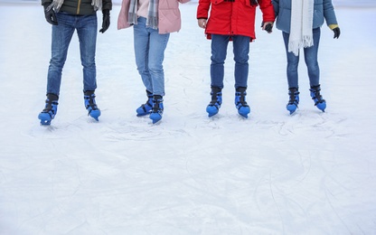 Photo of Friends skating along ice rink outdoors, closeup. Space for text