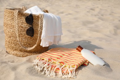 Beach bag, towel, blanket, sunglasses and sunscreen on sand Photo of Beach bag, towel, blanket, sunglasses and sunscreen on sand