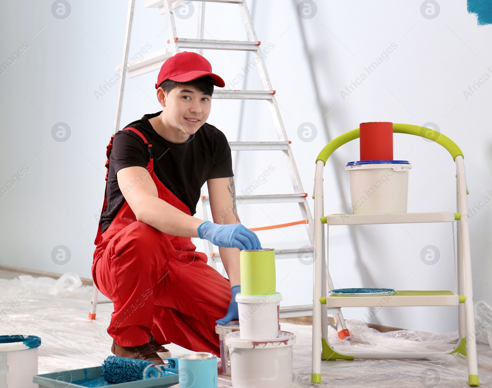 Male decorator with paint buckets indoors Photo of Male decorator with paint buckets indoors