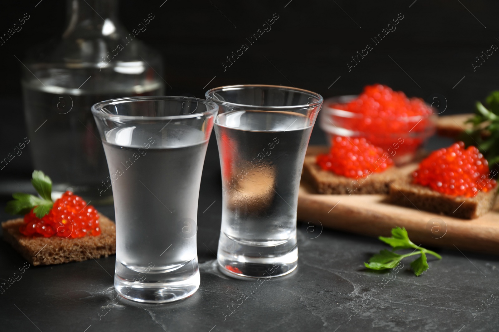 Cold Russian vodka and sandwiches with red caviar on black table, closeup Photo of Cold Russian vodka and sandwiches with red caviar on black table, closeup