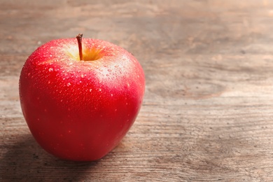Ripe red apple with water drops on wooden background Photo of Ripe red apple with water drops on wooden background