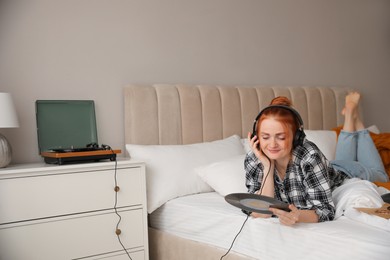 Young woman listening to music with turntable in bedroom Photo of Young woman listening to music with turntable in bedroom