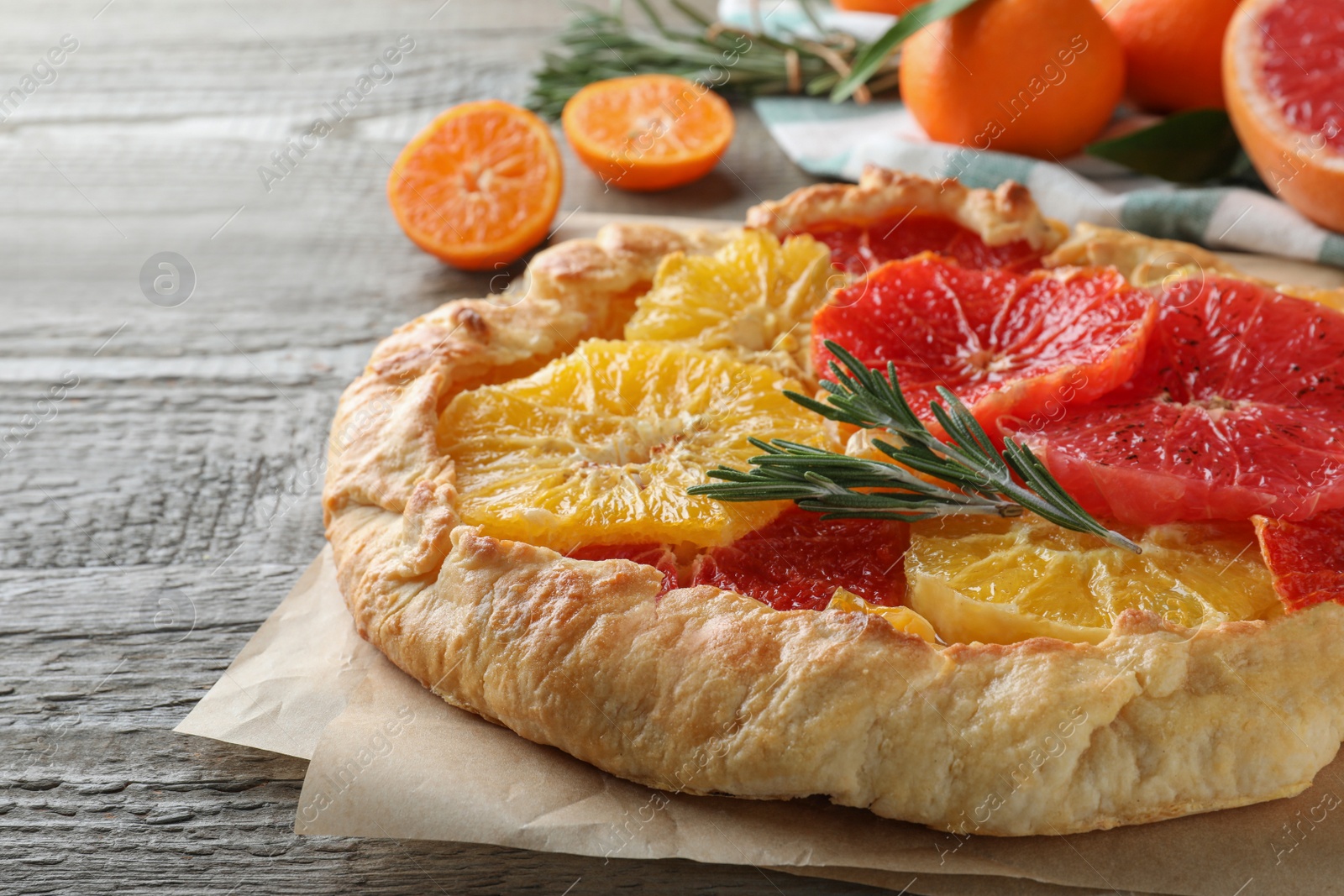 Delicious galette with citrus fruits and rosemary on wooden table, closeup Photo of Delicious galette with citrus fruits and rosemary on wooden table, closeup