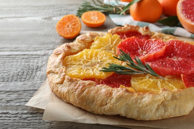 Delicious galette with citrus fruits and rosemary on wooden table, closeup Photo of Delicious galette with citrus fruits and rosemary on wooden table, closeup