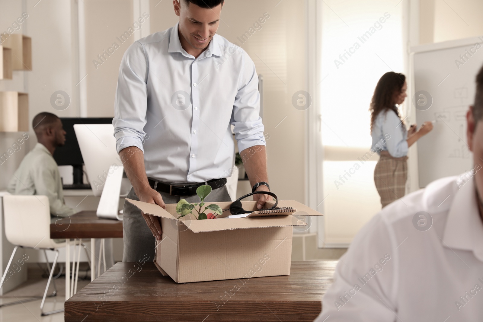 New coworker unpacking box with personal items at workplace in office Photo of New coworker unpacking box with personal items at workplace in office