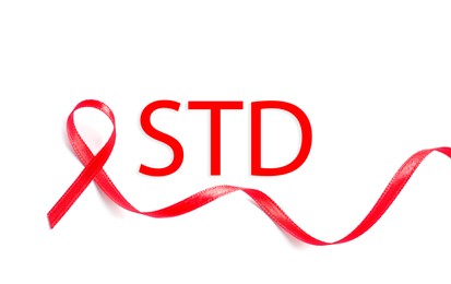 Red awareness ribbon and abbreviation STD on white background, top view Image of Red awareness ribbon and abbreviation STD on white background, top view