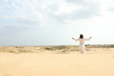 Jesus Christ raising hands in desert, back view. Space for text Photo of Jesus Christ raising hands in desert, back view. Space for text