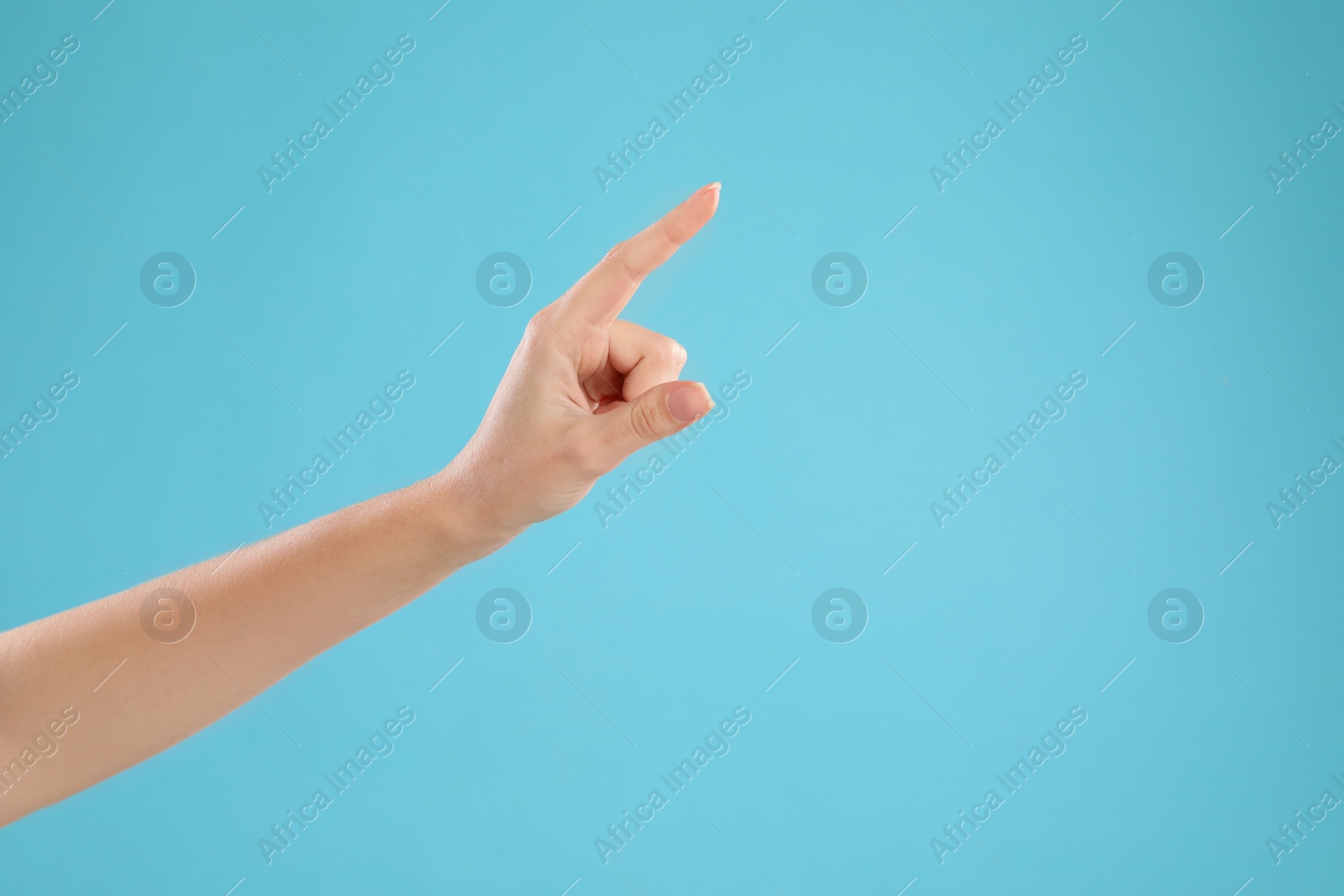 Closeup view of woman pointing at something on light blue background, space for text. Finger gesture Photo of Closeup view of woman pointing at something on light blue background, space for text. Finger gesture