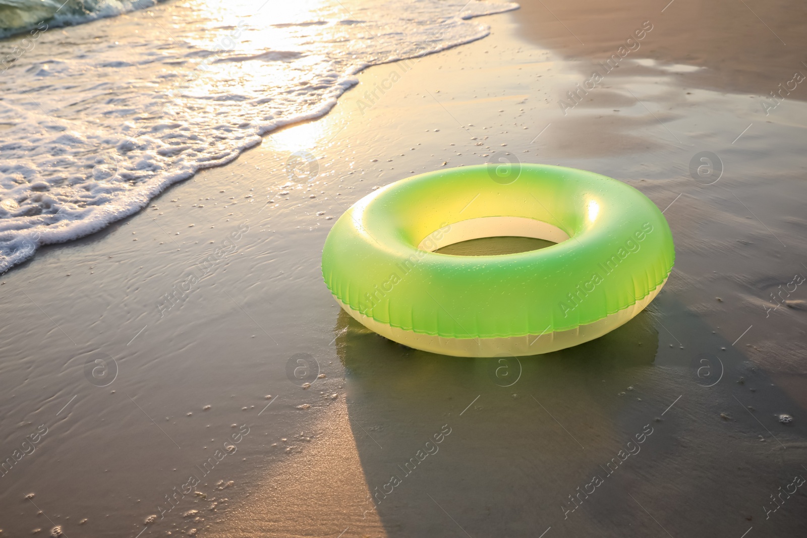 Light green inflatable ring on sunlit sandy beach near sea, space for text Photo of Light green inflatable ring on sunlit sandy beach near sea, space for text