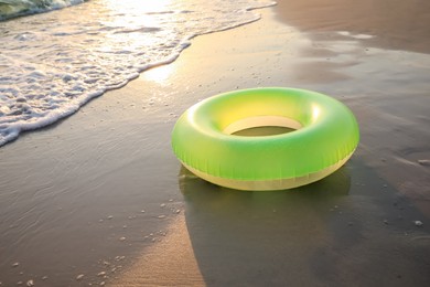 Light green inflatable ring on sunlit sandy beach near sea, space for text Photo of Light green inflatable ring on sunlit sandy beach near sea, space for text