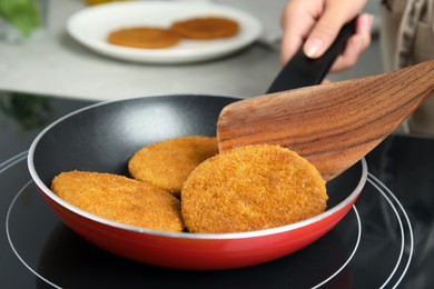 Woman cooking breaded cutlets in frying pan on stove, closeup Photo of Woman cooking breaded cutlets in frying pan on stove, closeup
