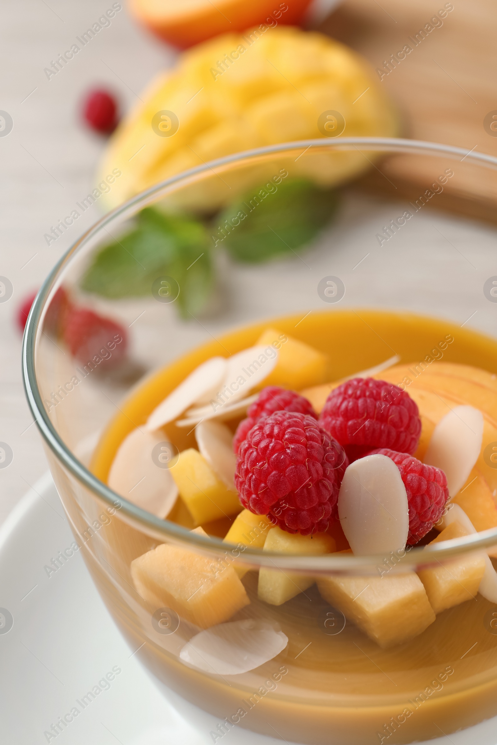 Delicious panna cotta with mango coulis, fresh fruit pieces and almond flakes in bowl, closeup Photo of Delicious panna cotta with mango coulis, fresh fruit pieces and almond flakes in bowl, closeup