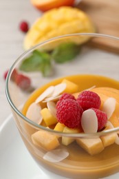 Delicious panna cotta with mango coulis, fresh fruit pieces and almond flakes in bowl, closeup Photo of Delicious panna cotta with mango coulis, fresh fruit pieces and almond flakes in bowl, closeup