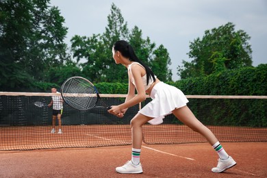 Man and woman playing tennis on court Photo of Man and woman playing tennis on court
