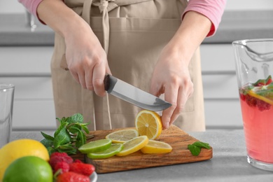 Woman preparing fresh lemonade on table Photo of Woman preparing fresh lemonade on table