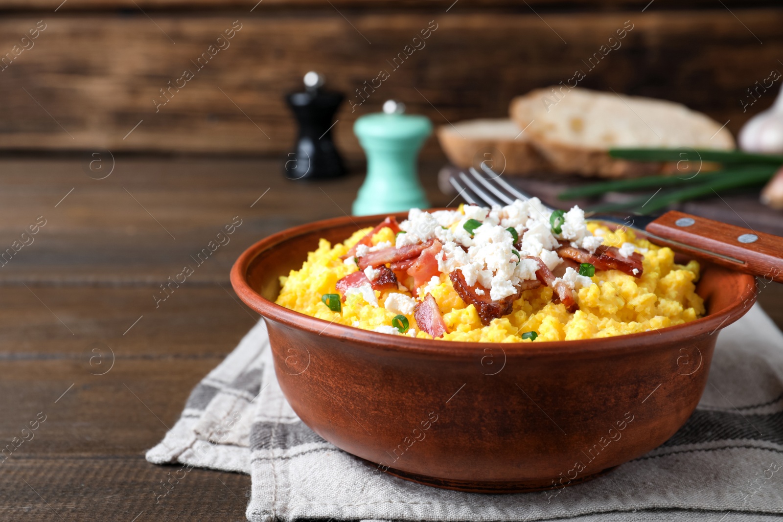 Tasty banosh served with brynza and pork cracklings in bowl on wooden table. Traditional Ukrainian dish Photo of Tasty banosh served with brynza and pork cracklings in bowl on wooden table. Traditional Ukrainian dish