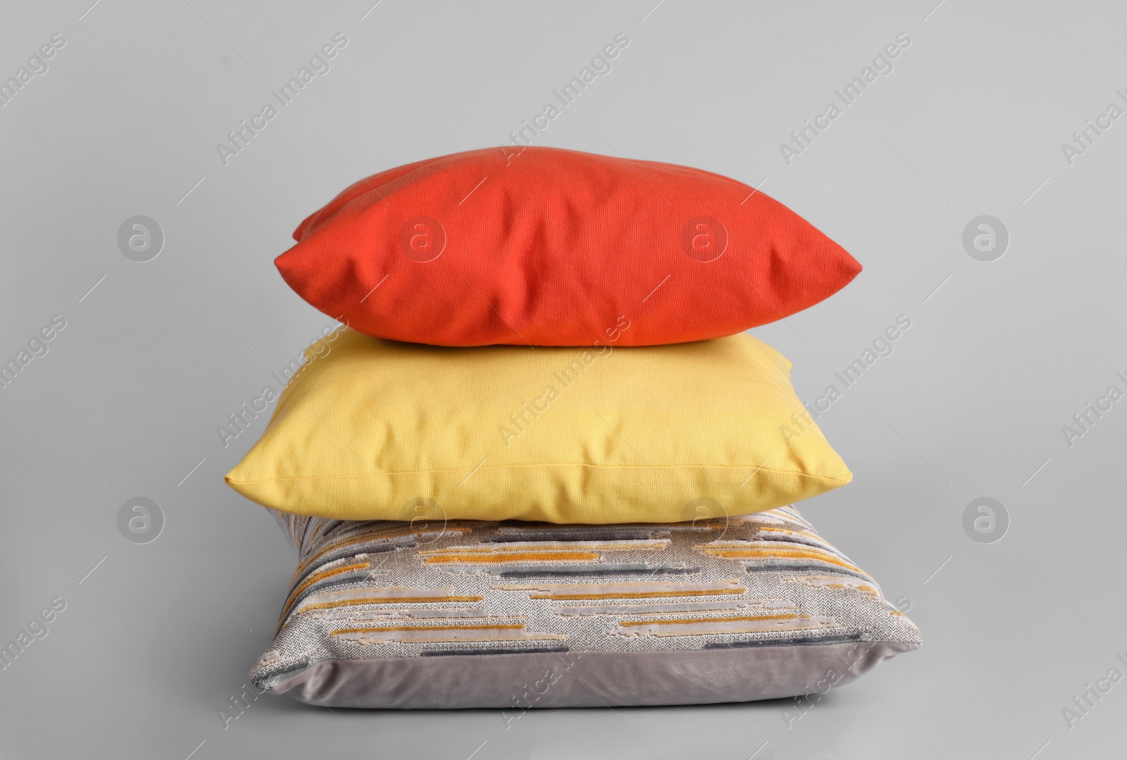 Stack of stylish soft pillows on grey background Photo of Stack of stylish soft pillows on grey background