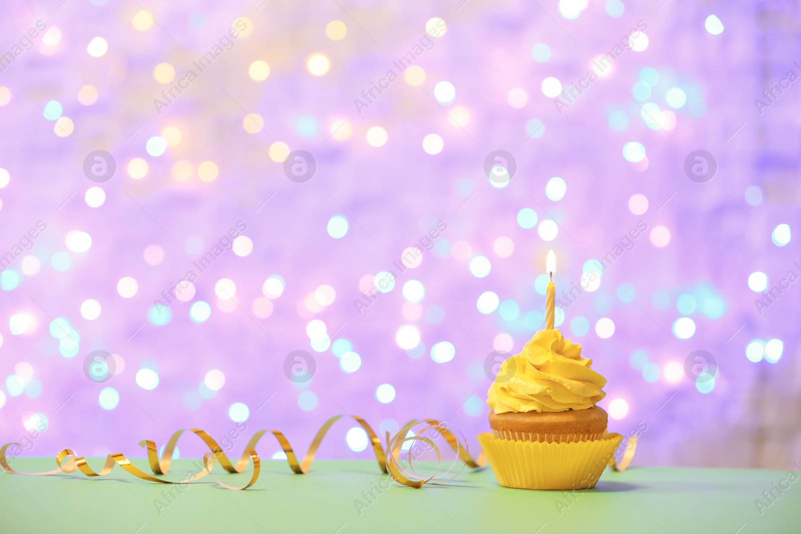 Birthday cupcake with candle against blurred lights Photo of Birthday cupcake with candle against blurred lights