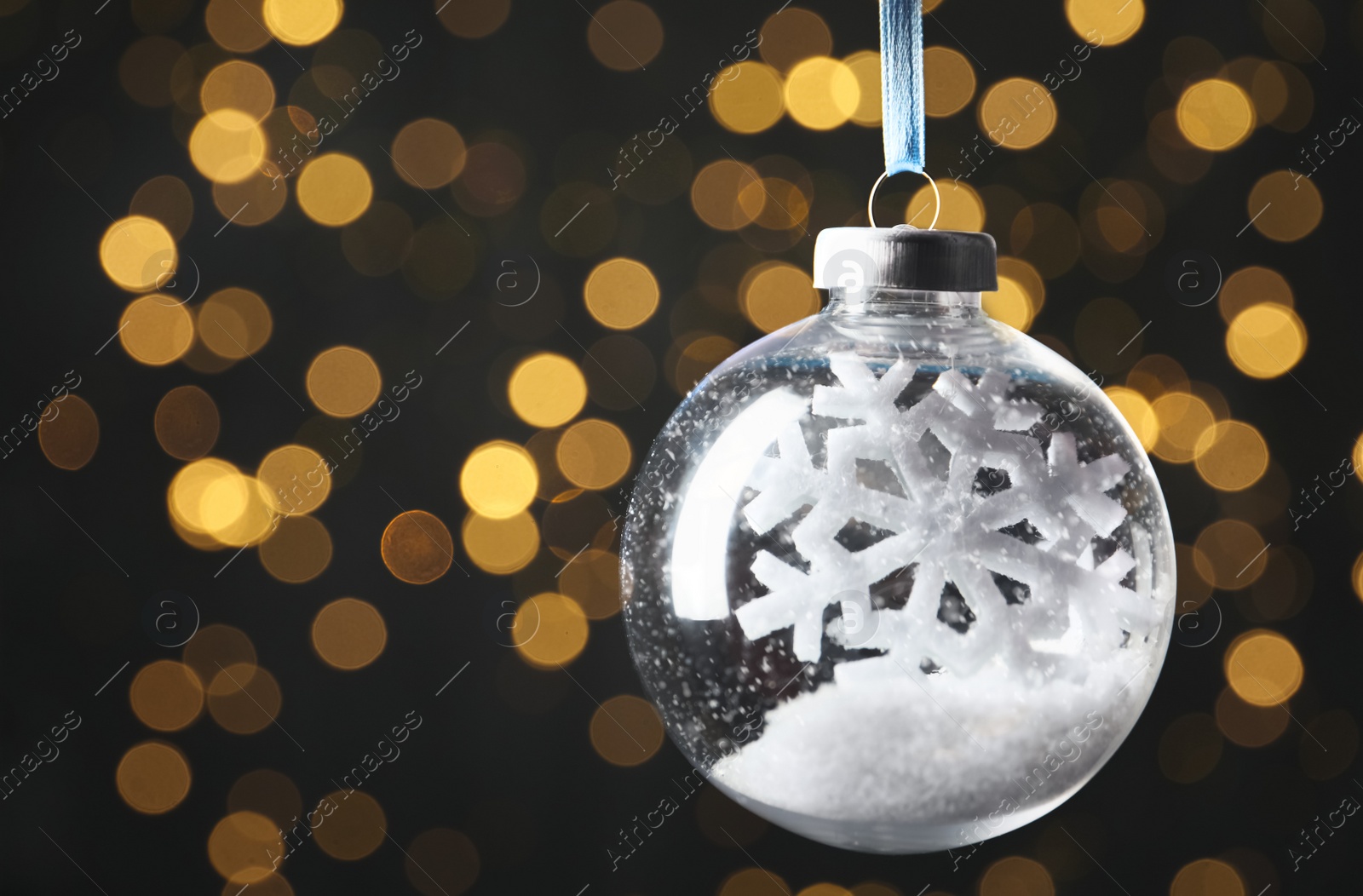 Decorative snow globe hanging against blurred festive lights, closeup. Space for text Photo of Decorative snow globe hanging against blurred festive lights, closeup. Space for text