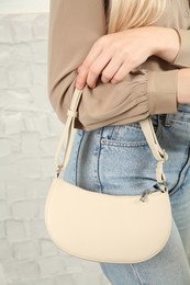 Woman with stylish baguette handbag near white wall, closeup Photo of Woman with stylish baguette handbag near white wall, closeup