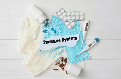 Paper piece with phrase Immune system and medical supplies on white wooden table, flat lay Photo of Paper piece with phrase Immune system and medical supplies on white wooden table, flat lay