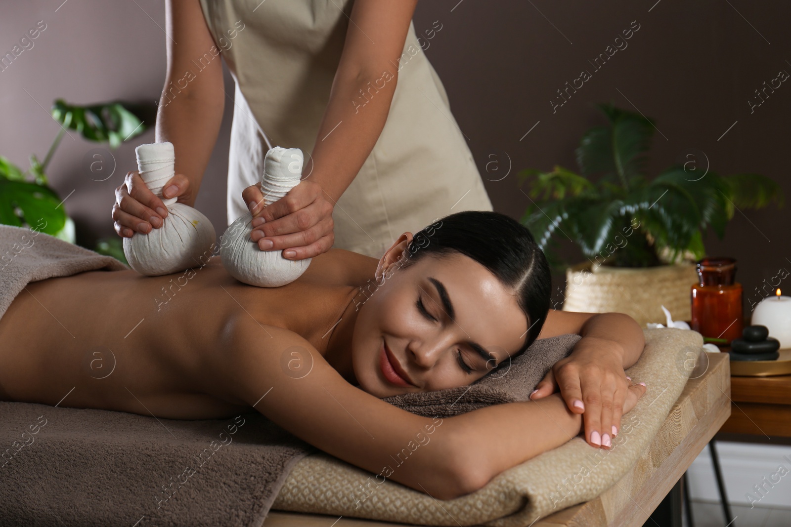 Young woman receiving herbal bag massage in spa salon Photo of Young woman receiving herbal bag massage in spa salon