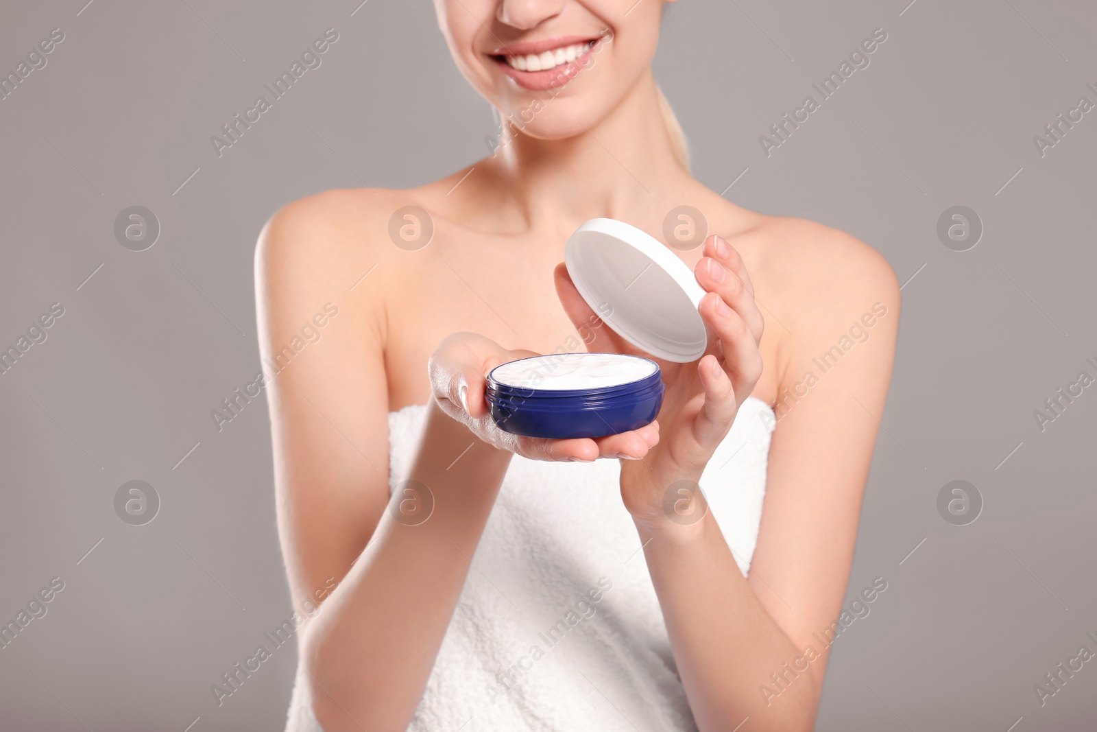 Young woman with jar of body cream on color background Photo of Young woman with jar of body cream on color background