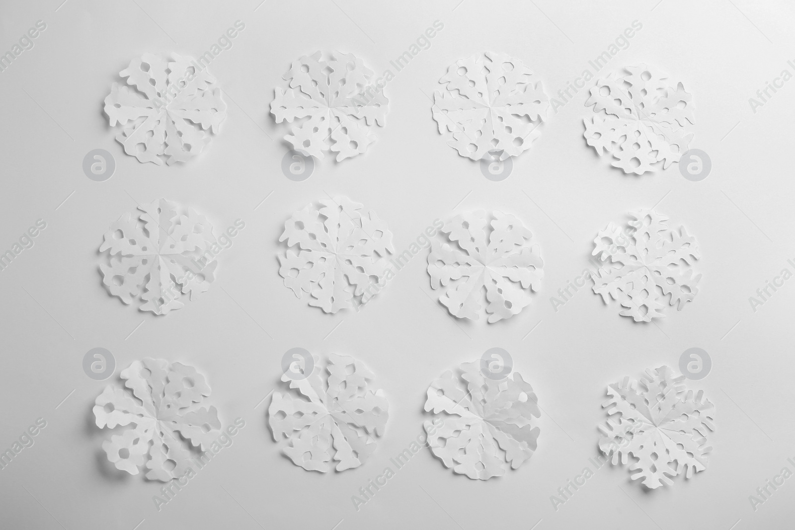 Many paper snowflakes on white background, flat lay Photo of Many paper snowflakes on white background, flat lay