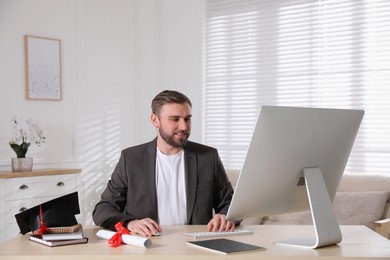 Happy student with graduation hat and diploma at workplace in office Photo of Happy student with graduation hat and diploma at workplace in office