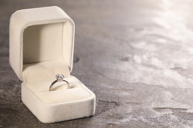 Beautiful engagement ring with gemstone in box on grey table. Space for text Photo of Beautiful engagement ring with gemstone in box on grey table. Space for text