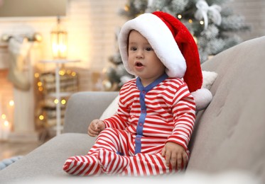 Cute baby in Santa hat sitting on sofa at home. Christmas celebration Image of Cute baby in Santa hat sitting on sofa at home. Christmas celebration