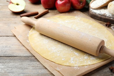 Rolling pin, raw dough and ingredients on wooden table, closeup. Baking apple pie Photo of Rolling pin, raw dough and ingredients on wooden table, closeup. Baking apple pie