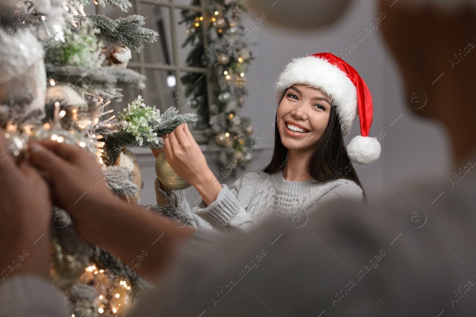 Happy young couple decorating Christmas tree together at home Photo of Happy young couple decorating Christmas tree together at home