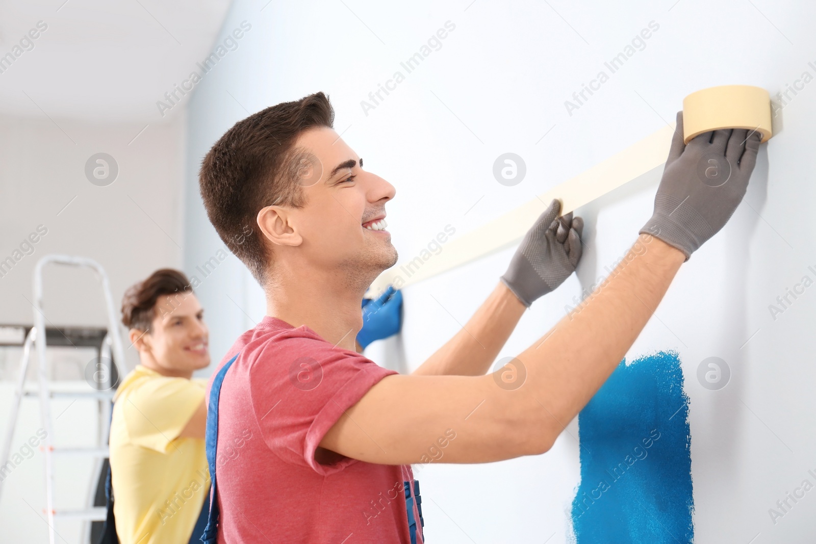 Male decorators working with tape indoors Photo of Male decorators working with tape indoors