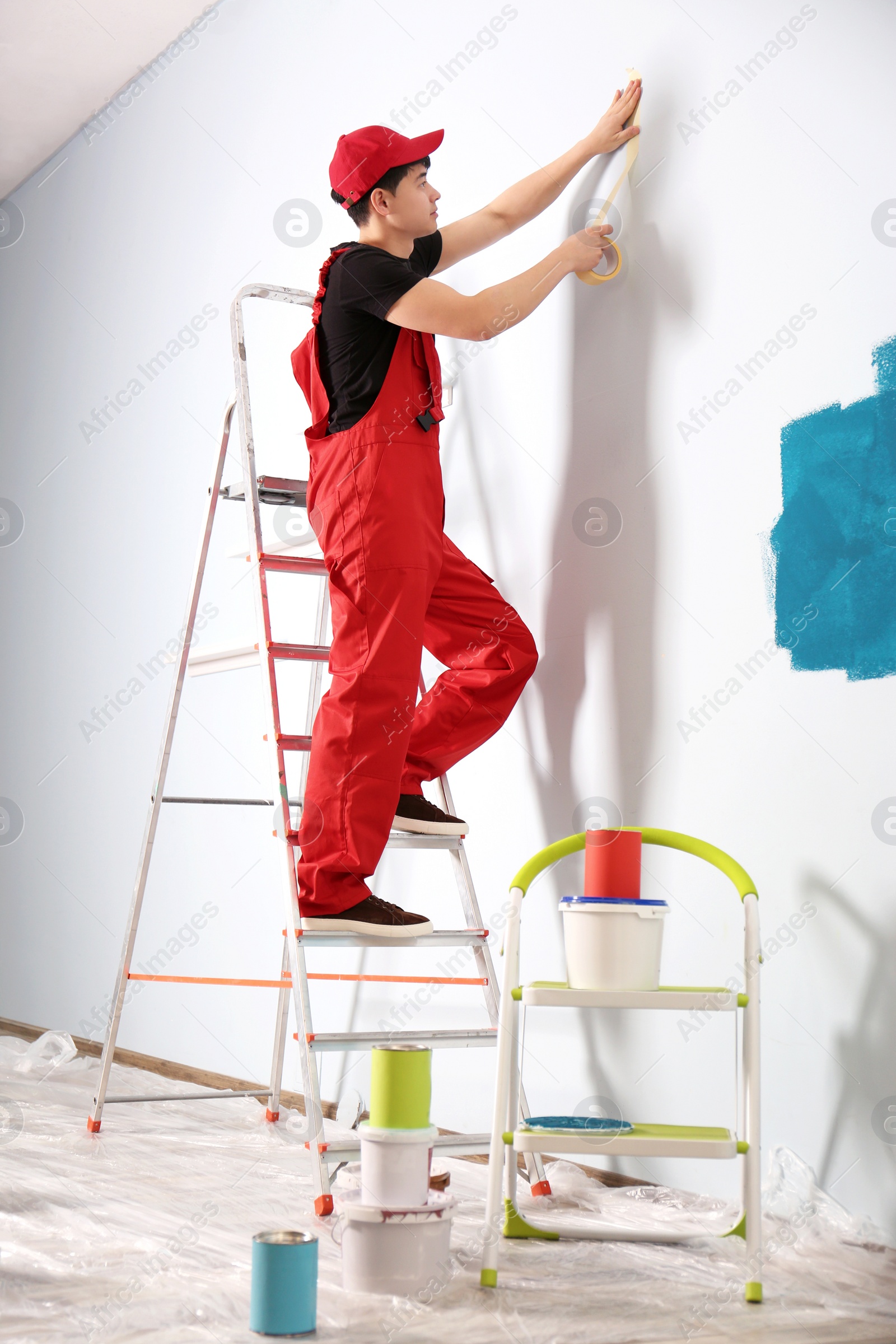 Male decorator working with tape indoors Photo of Male decorator working with tape indoors