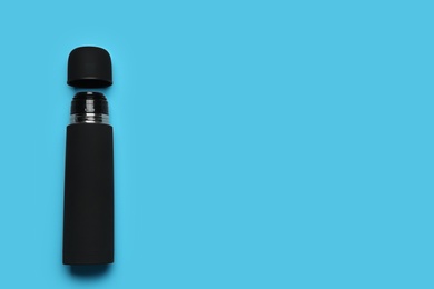 Black thermos on light blue background, top view. Space for text Photo of Black thermos on light blue background, top view. Space for text