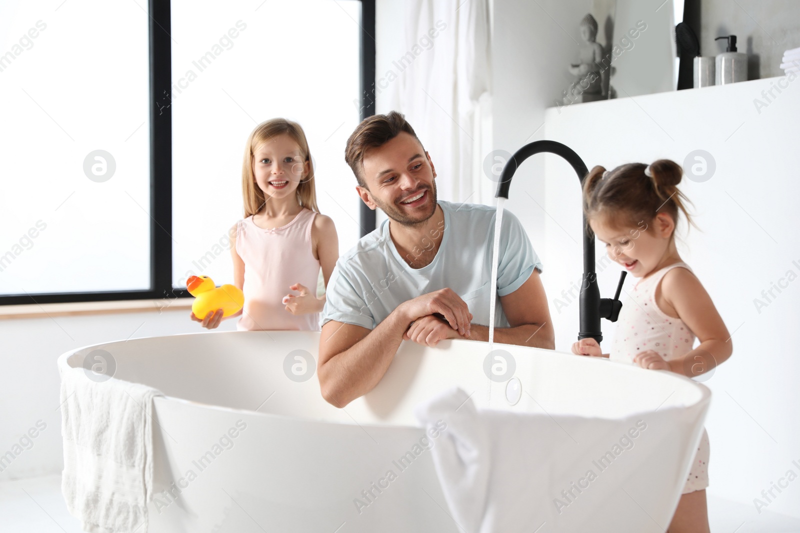 Photo of Young father with little daughters in bathroom